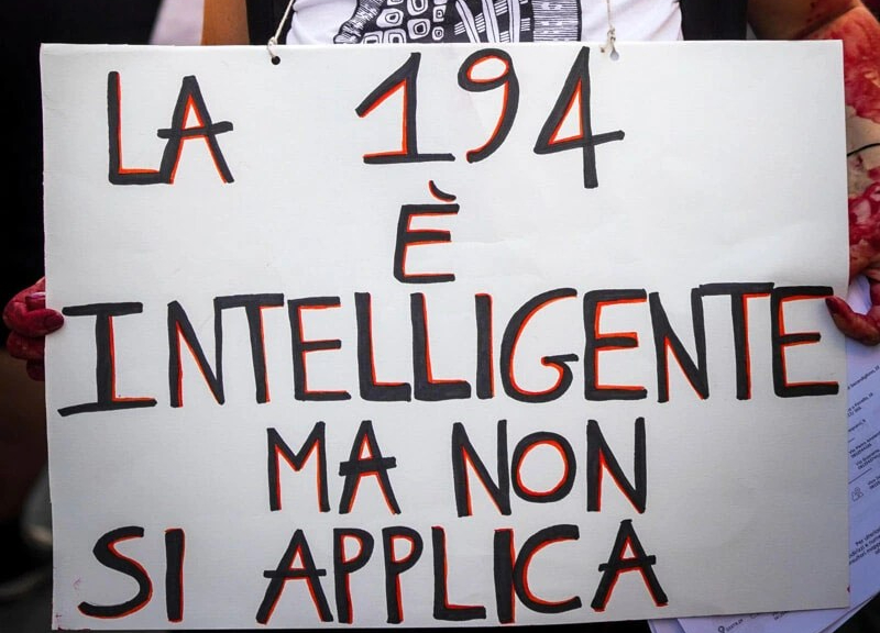 Manifestante con cartello al collo che recita "la 194 è intelligente ma non si applica"